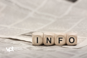 Eine Zeitung als Untergrund und darauf Würfel mit der Aufschrift "Info"